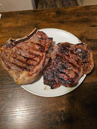 two steaks on a plate on a wooden table